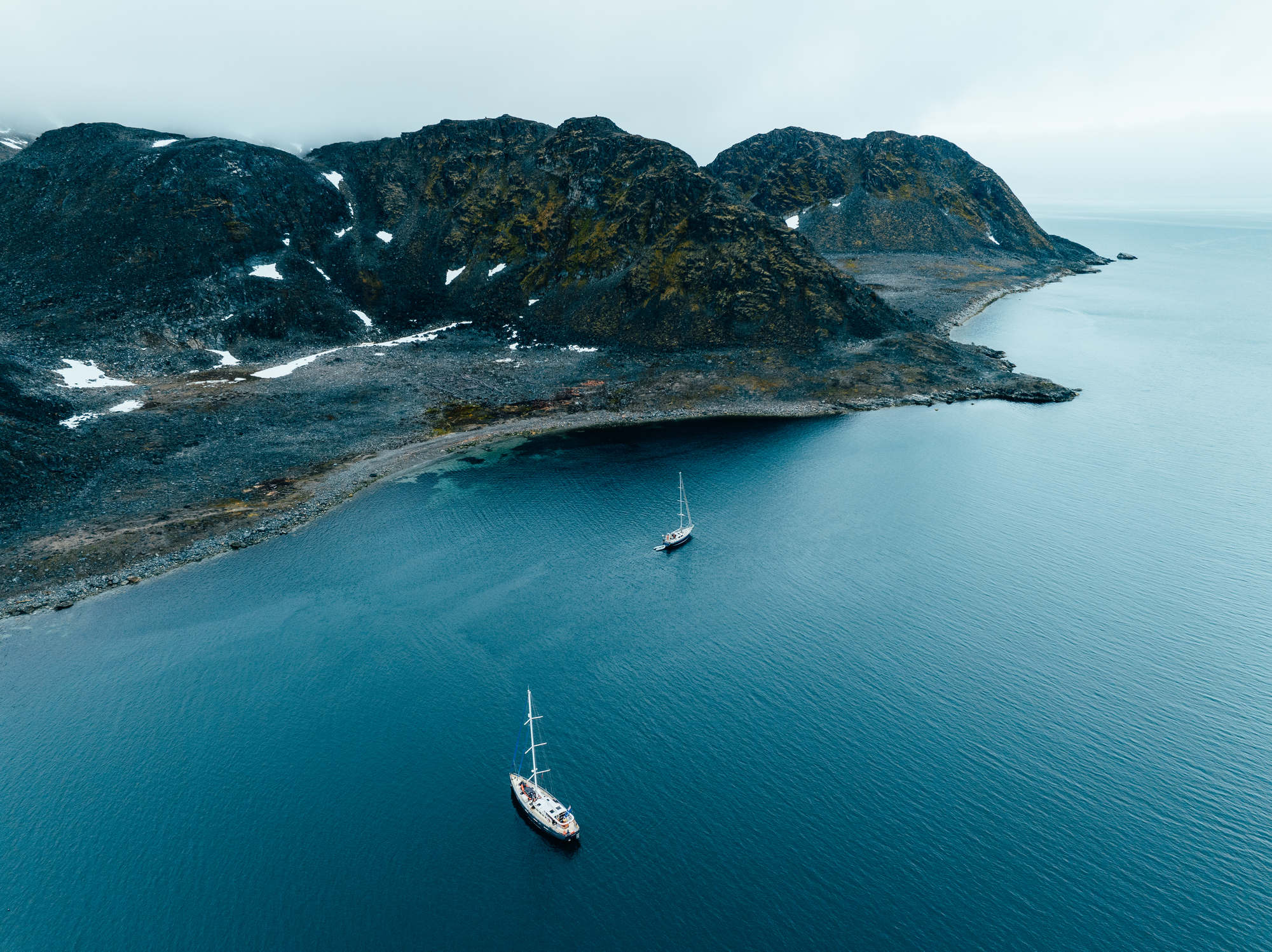 Valiente alongside another boat in front of mountains