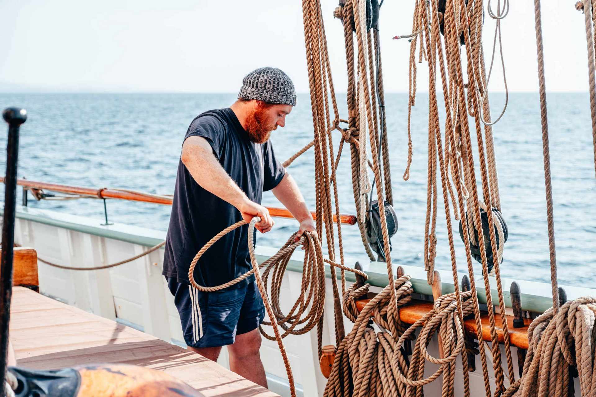 Man working the ropes on a tall ship at sea