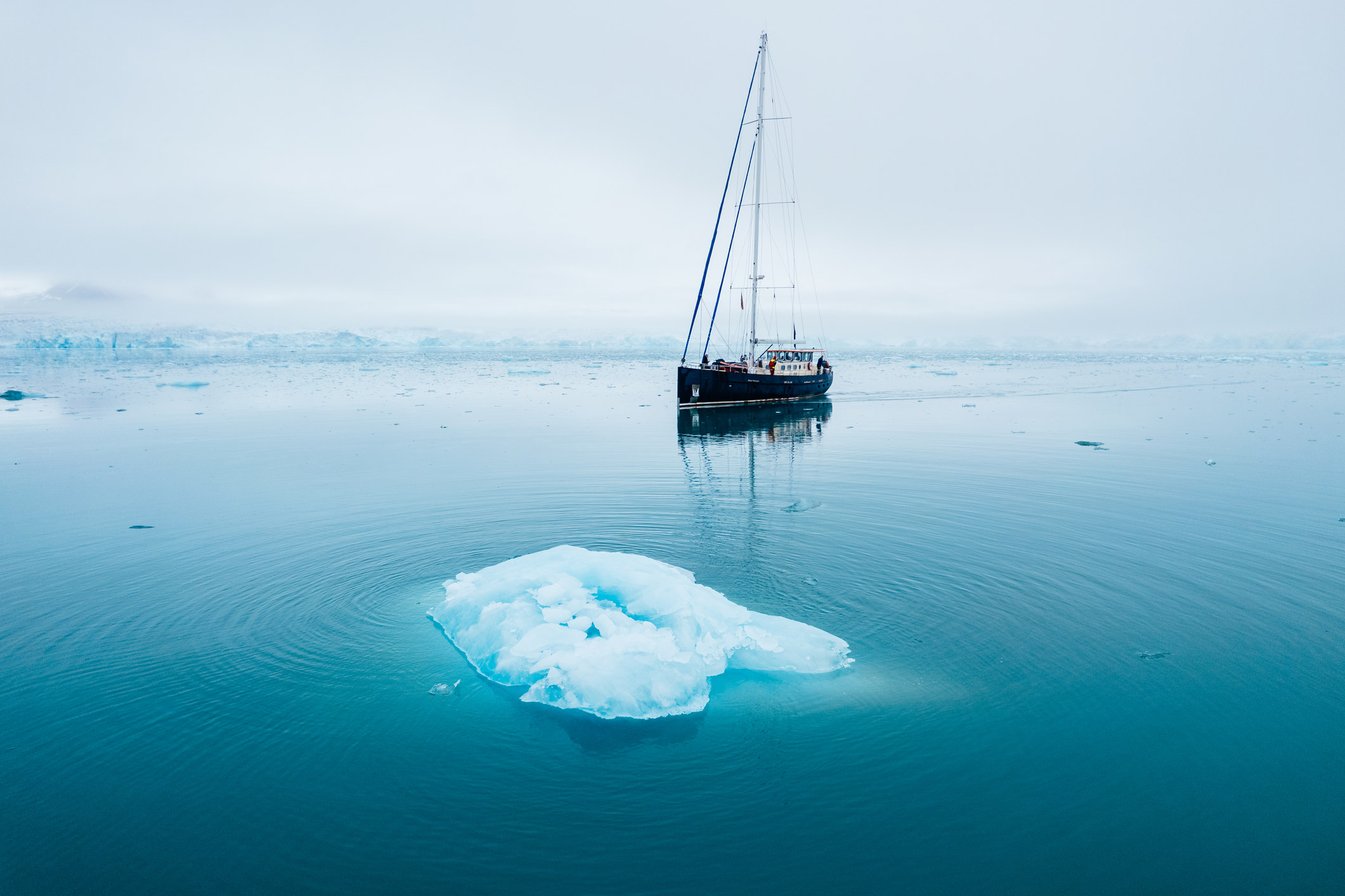 Sailboat in the arctic next to an ice berg