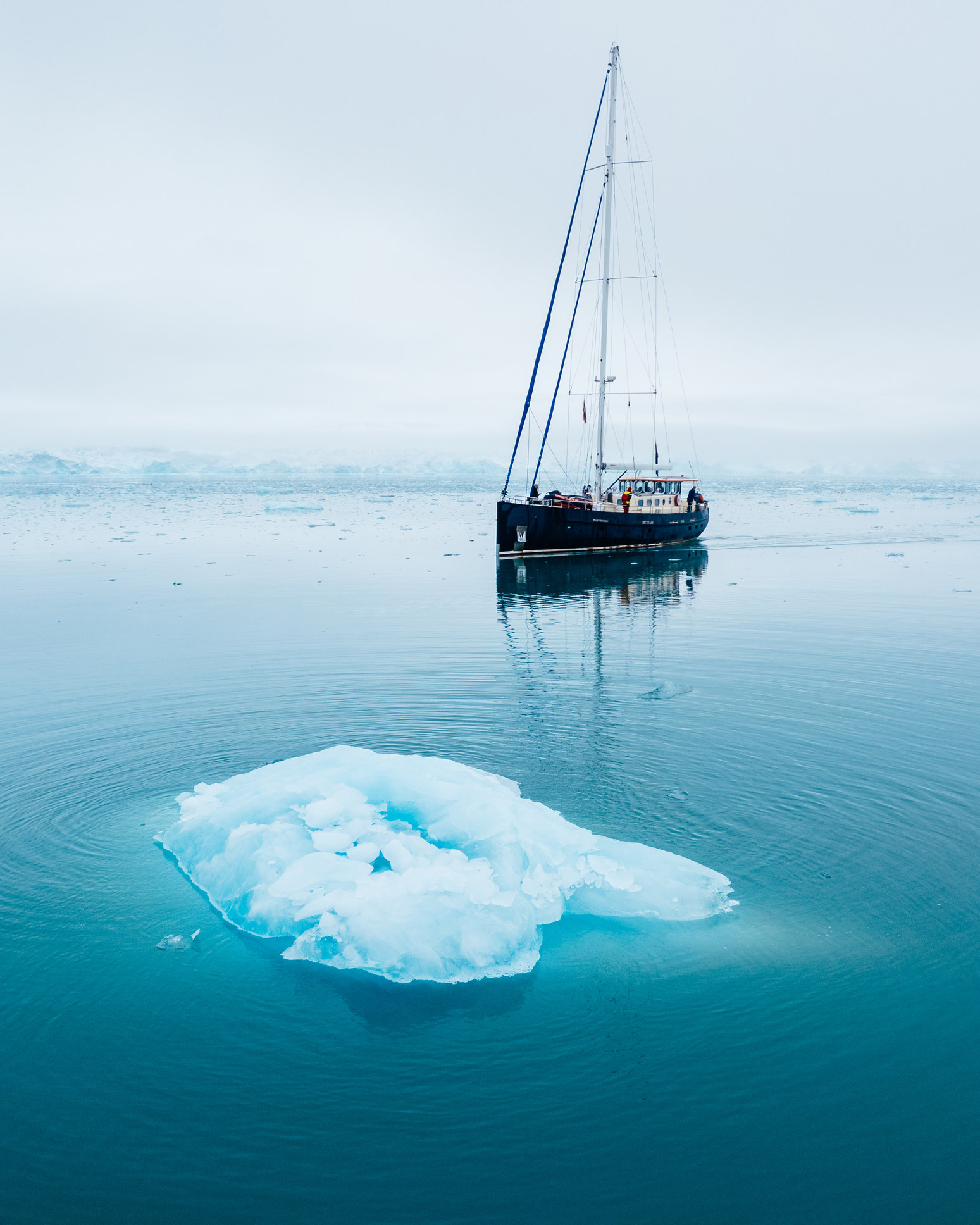 Sail boat in front of small ice berg