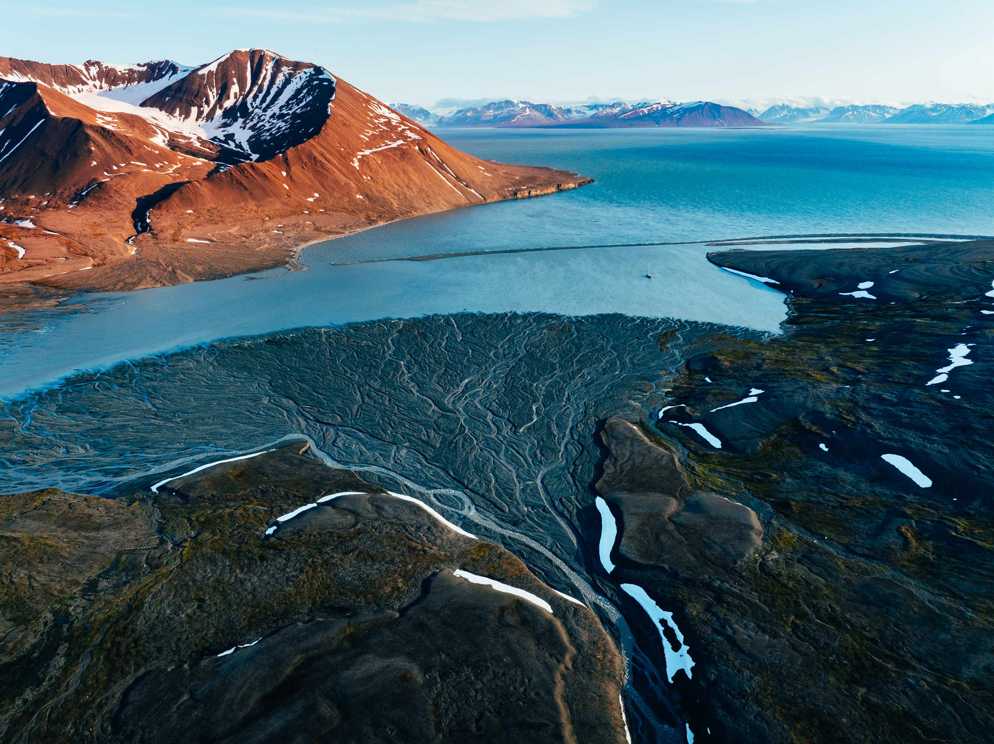 Arctic sunset with braided river and sail boat