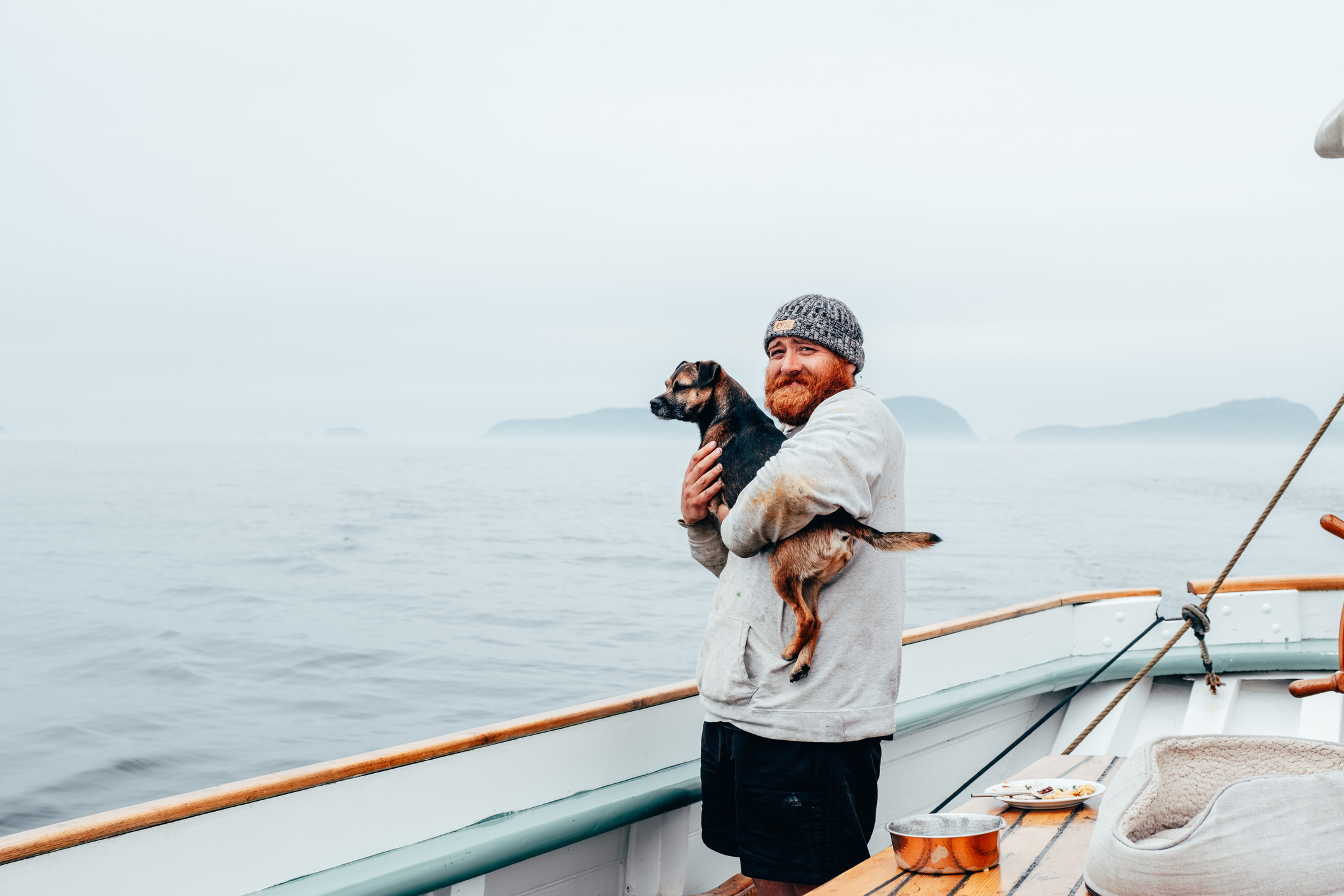 Man holding a dog on a ship at sea