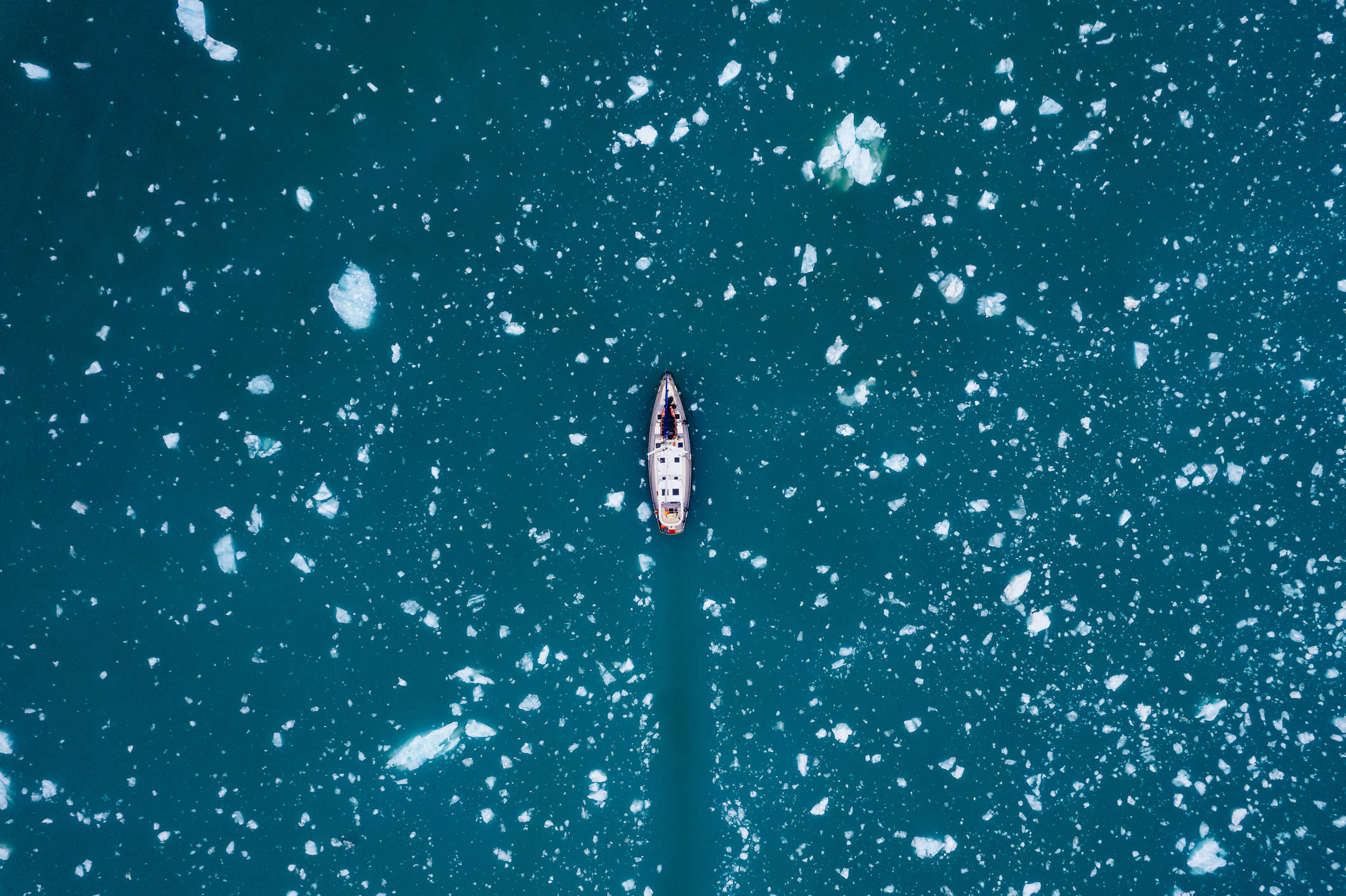 Top down view of sail boat sailing through ice in the arctic
