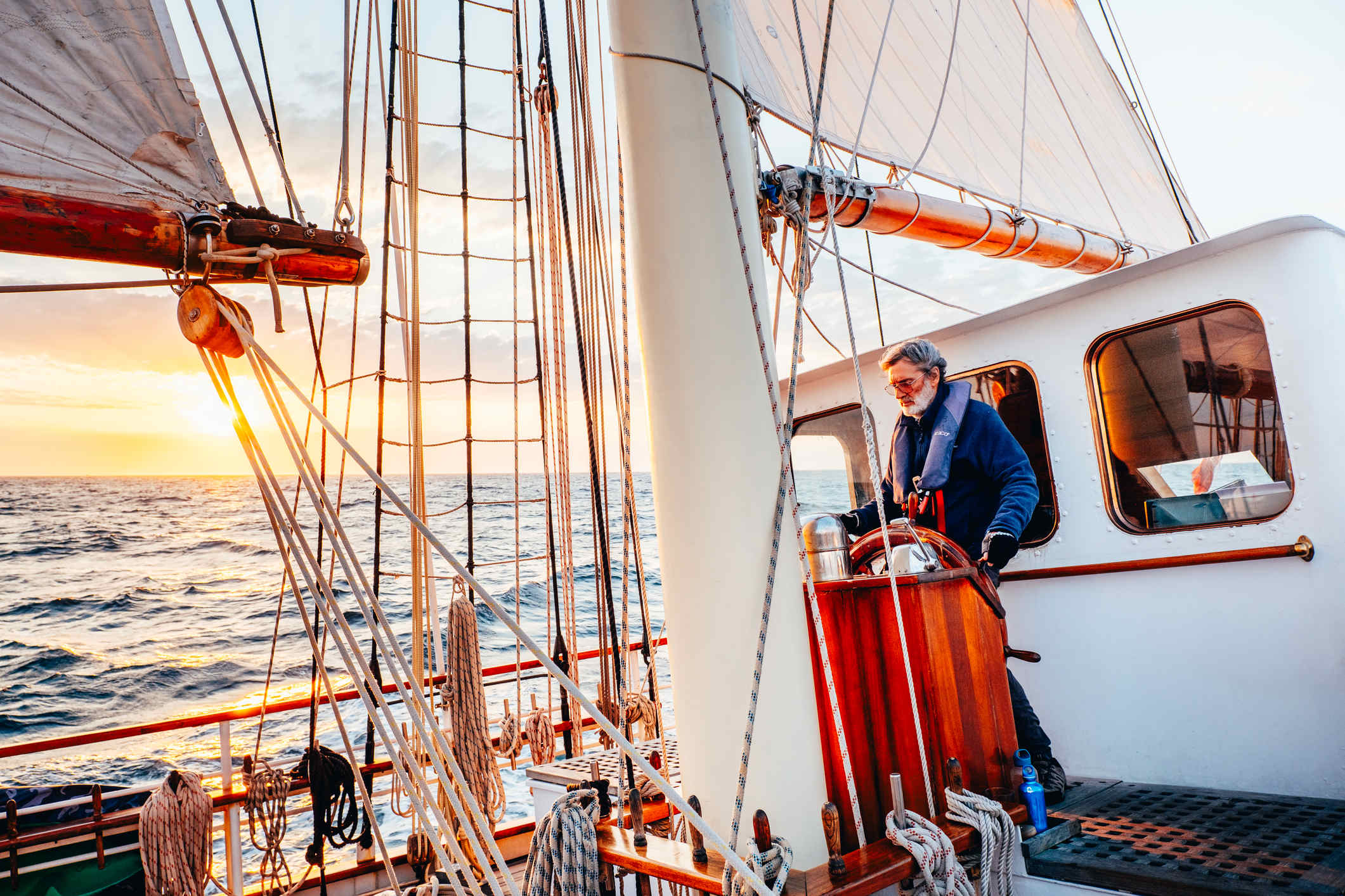 Man at the helm of a ship at sunset