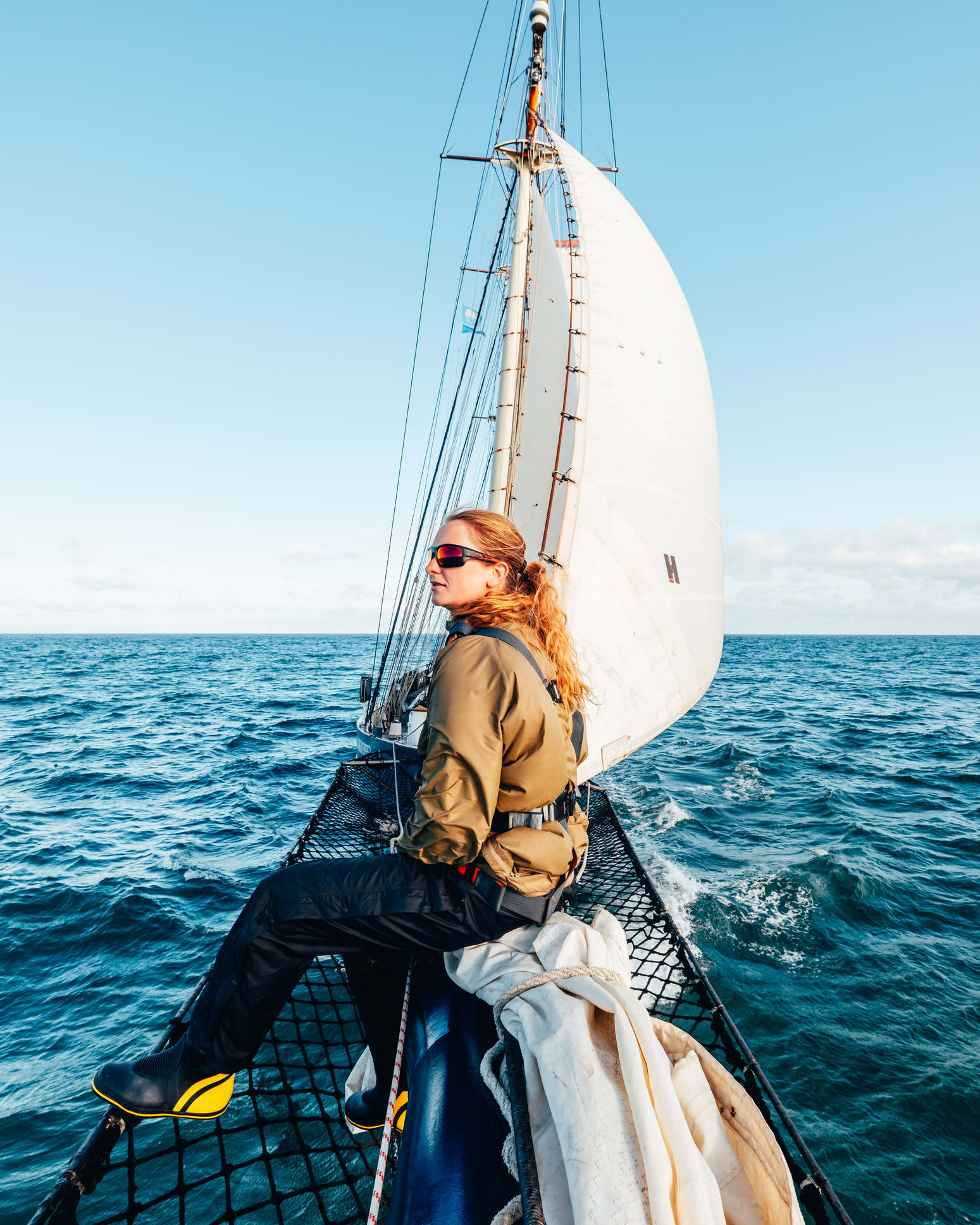 Woman sat on the bowsprit of a ship at sea