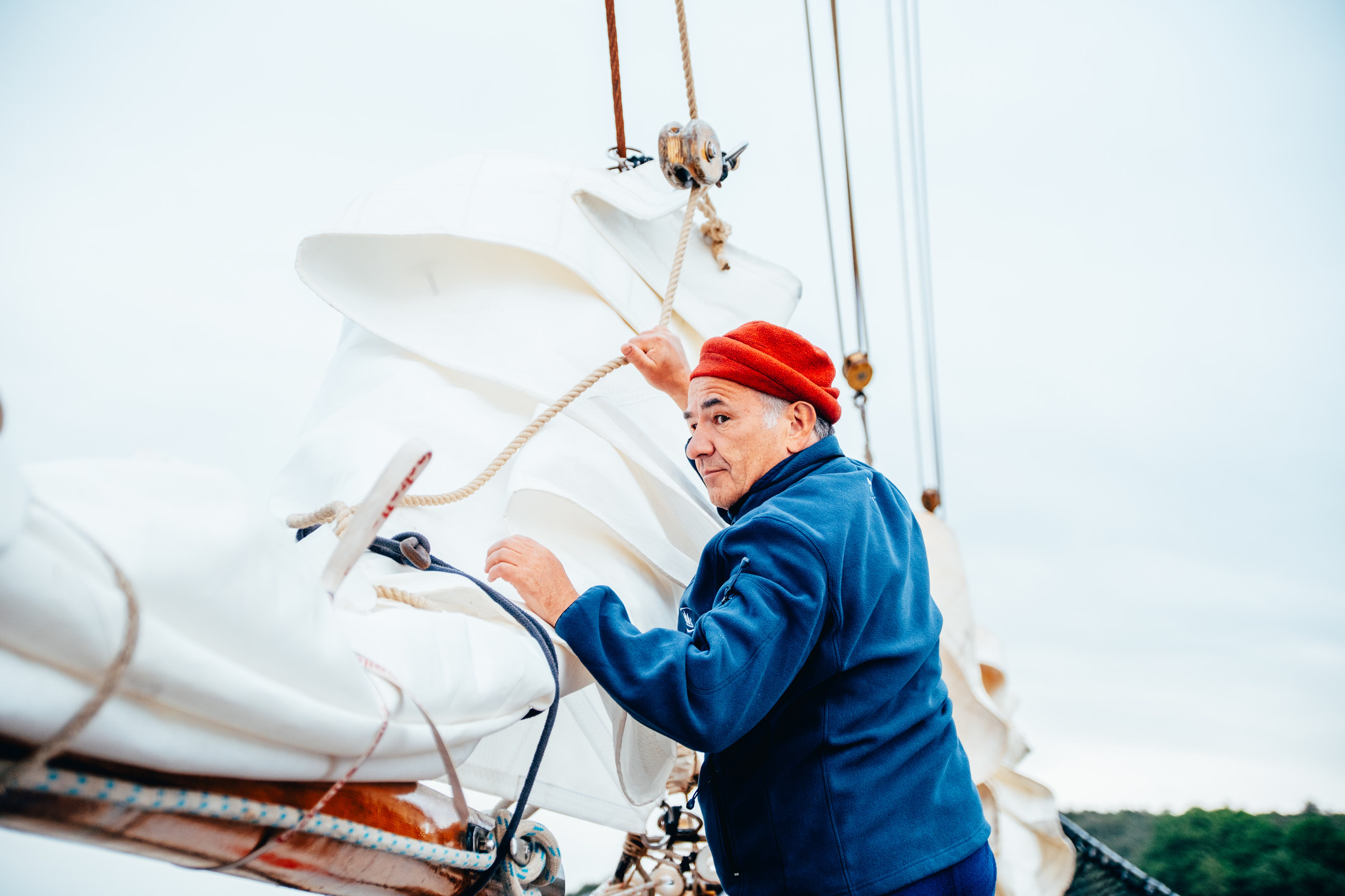 Man folding the jibs on a tall ship