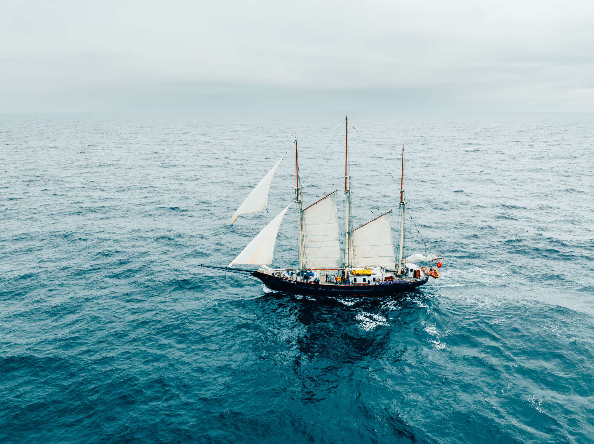 Blue clipper sailing in dramatic weather